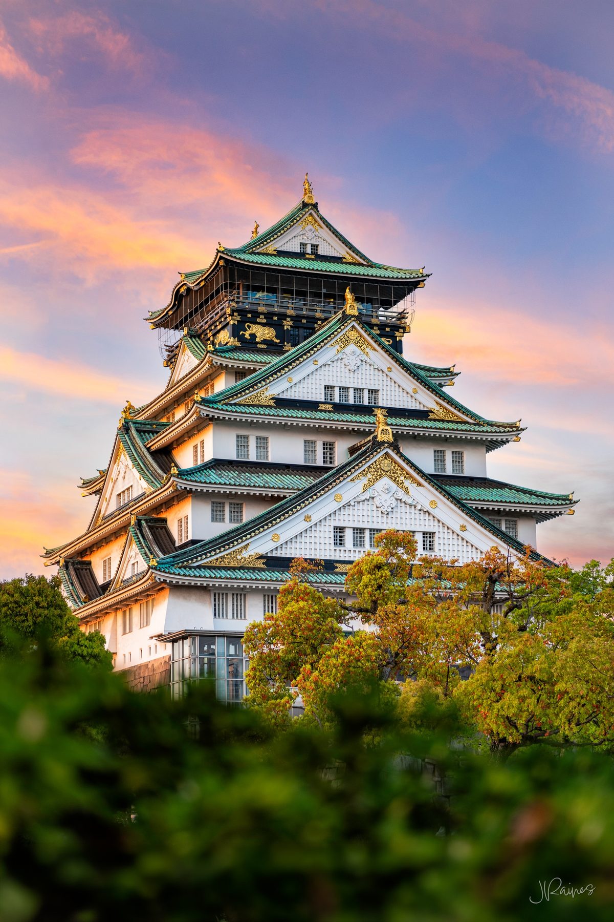 Osaka castle towering over the treetops at dusk