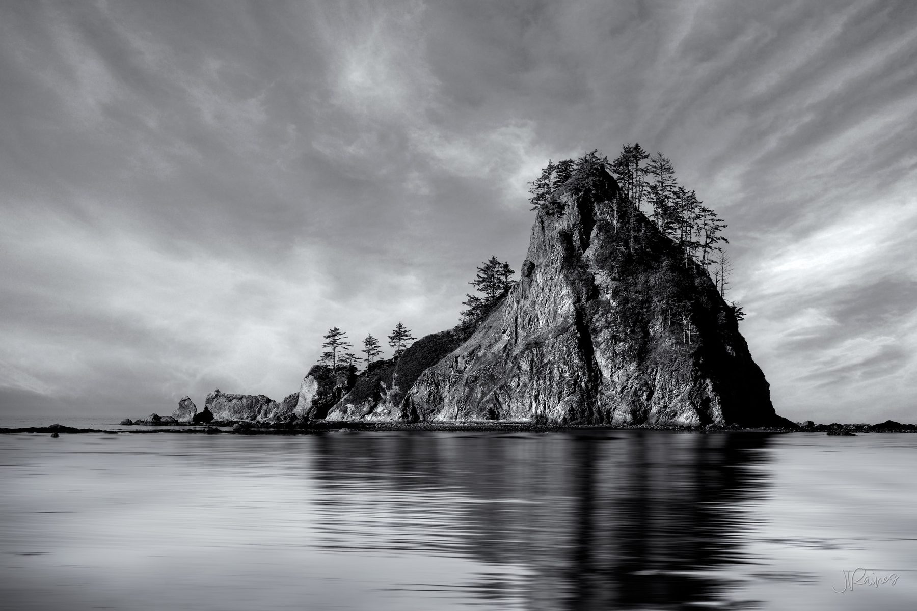 A sea stack off the Olympic National Park coast in Washington, mirrored in the wet sand at low tide