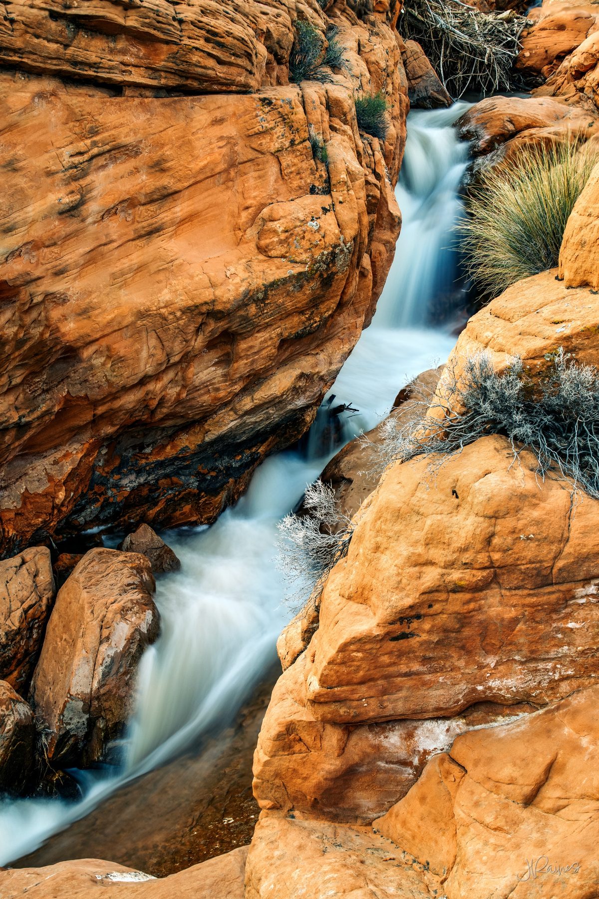 Waterfall flowing between red desert sandstone of Utah