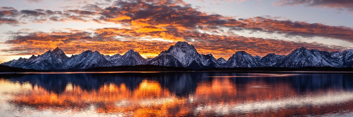 Tetons mountain range reflecting in lake at sunset