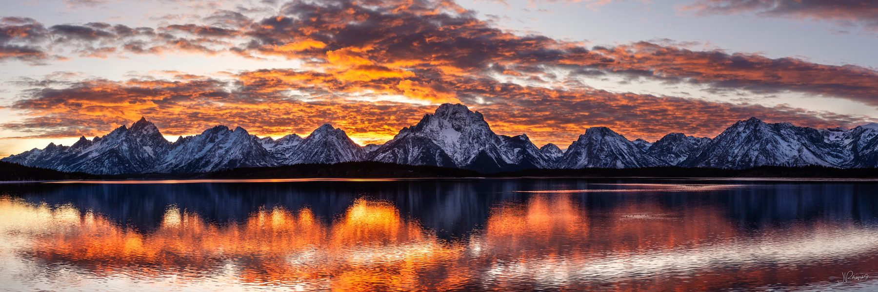 Tetons mountain range reflecting in lake at sunset