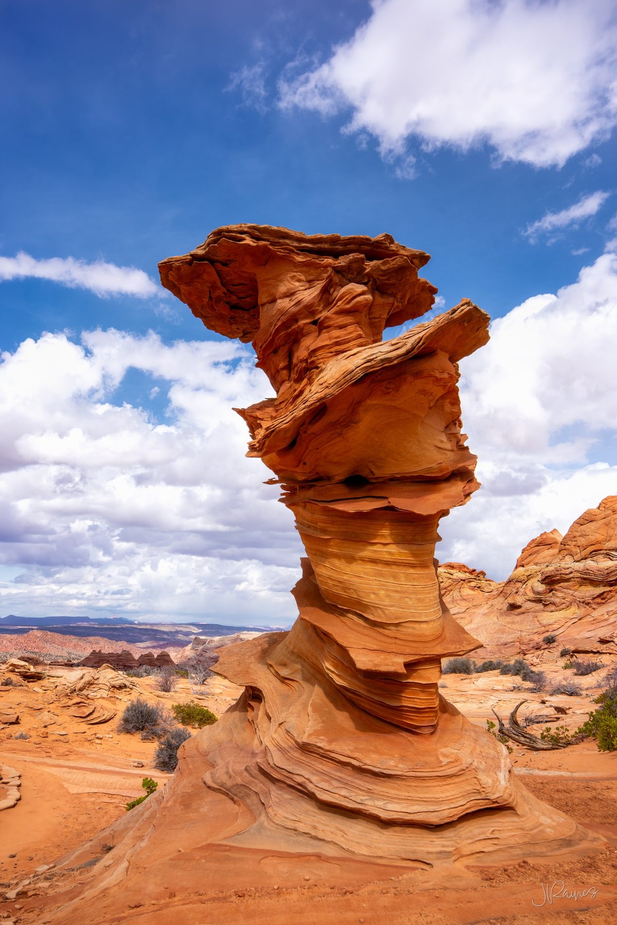 Control Tower, a striated sandstone formation at Vermilion Cliffs, Arizona, against a deep blue sky with clouds