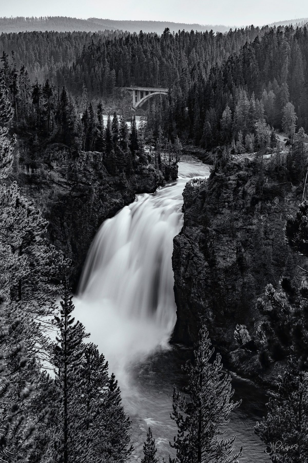 A waterfall in Yellowstone National Park, worked in black and white so the falling water reads as a single continuous shape against the dark canyon