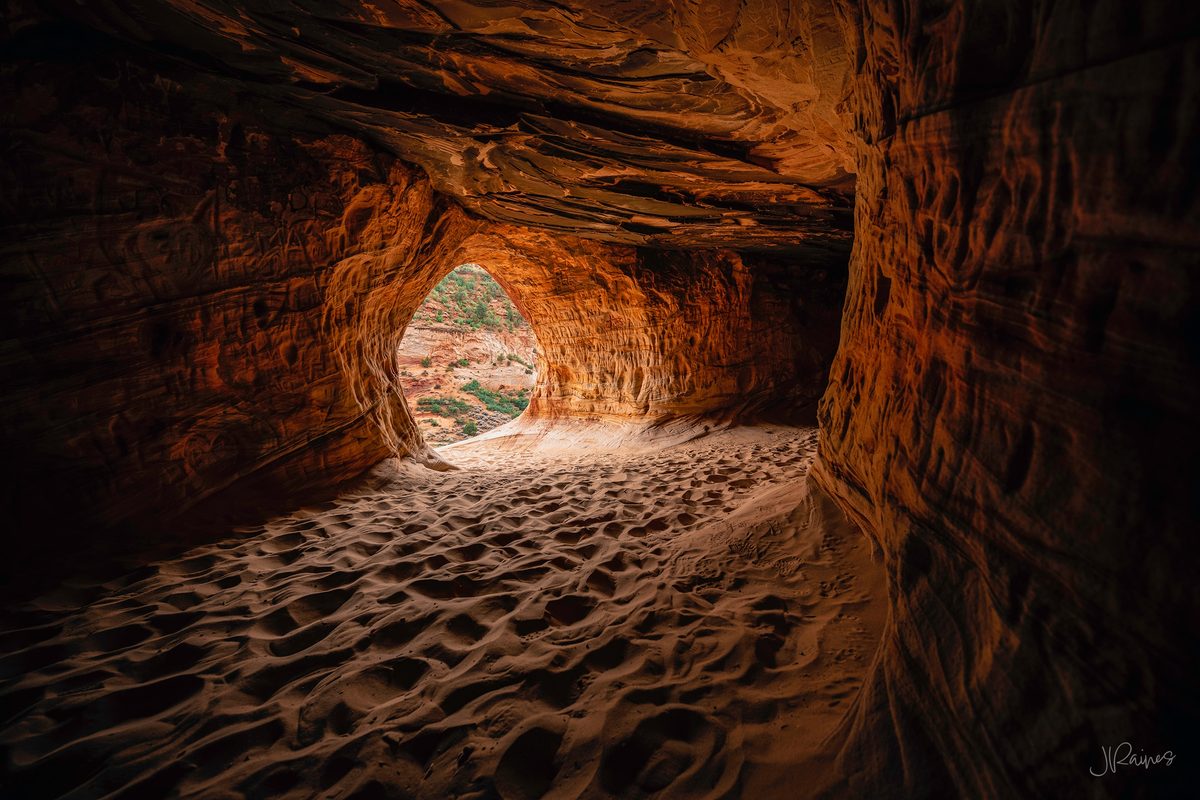 A wind-carved sandstone chamber near Kanab, Utah, with an opening framing the desert beyond