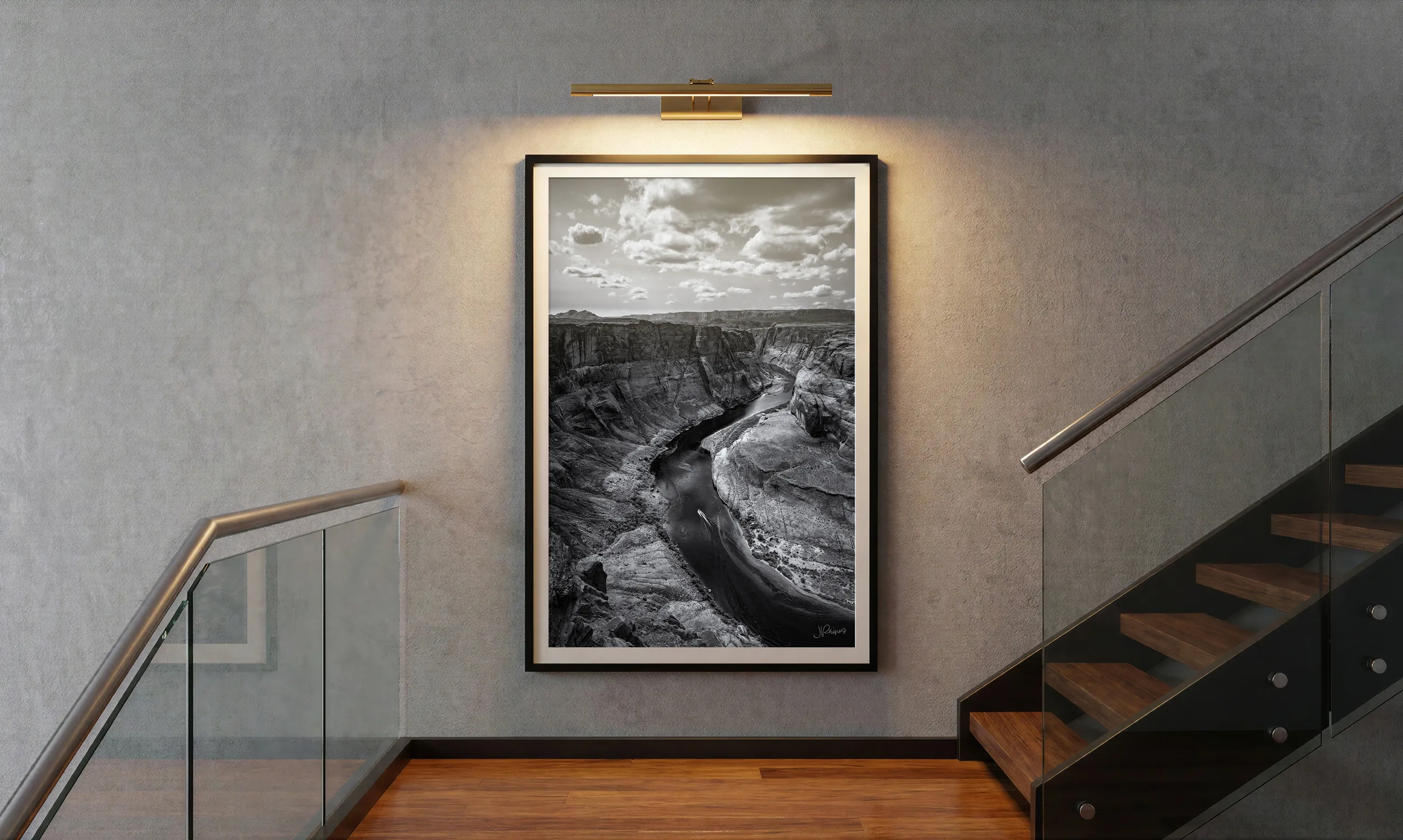 Half Life, a black and white framed print on a stair landing, lit by a warm brass picture light mounted close above the frame