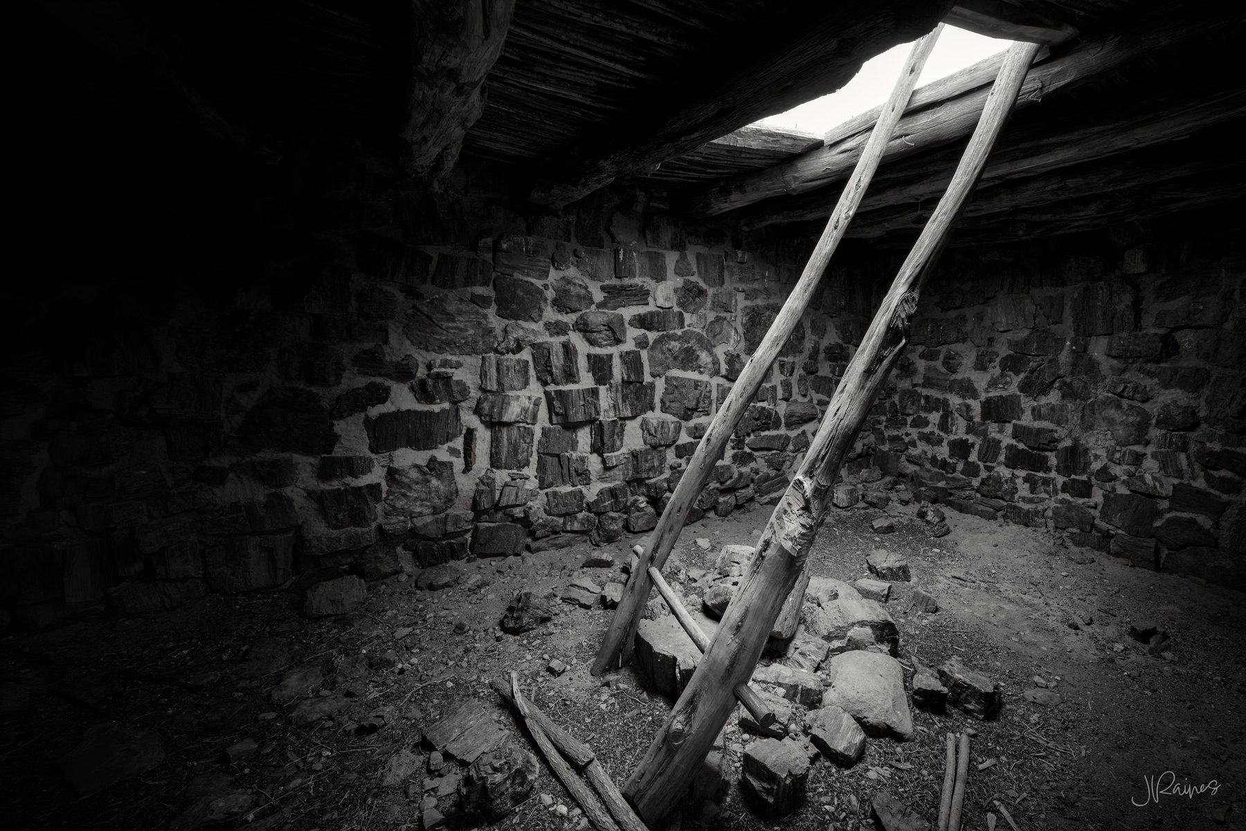 Ladder poles rising toward the roof opening inside Agate House, a pueblo built from petrified wood, Petrified Forest National Park, Arizona