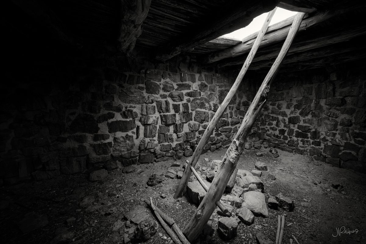 Ladder poles rising toward the roof opening inside Agate House, a pueblo built from petrified wood, Petrified Forest National Park, Arizona