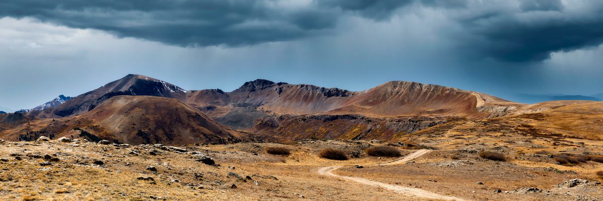 Road leading up to a Continental Divide mountain range with storm clouds, Roaring Fork Valley, Colorado