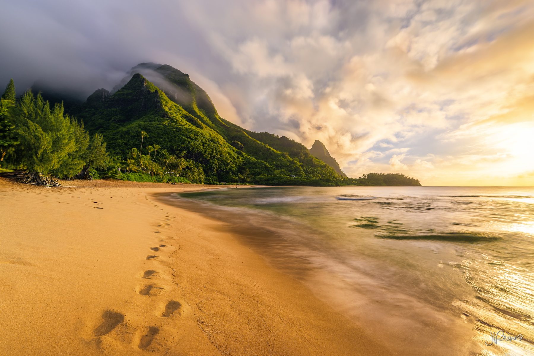 Surf running up the sand on Kauai, Hawaii, under low sun