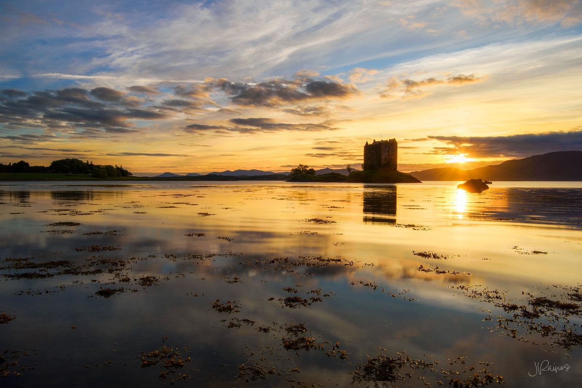 A tower house standing over still water in Glencoe, Scotland